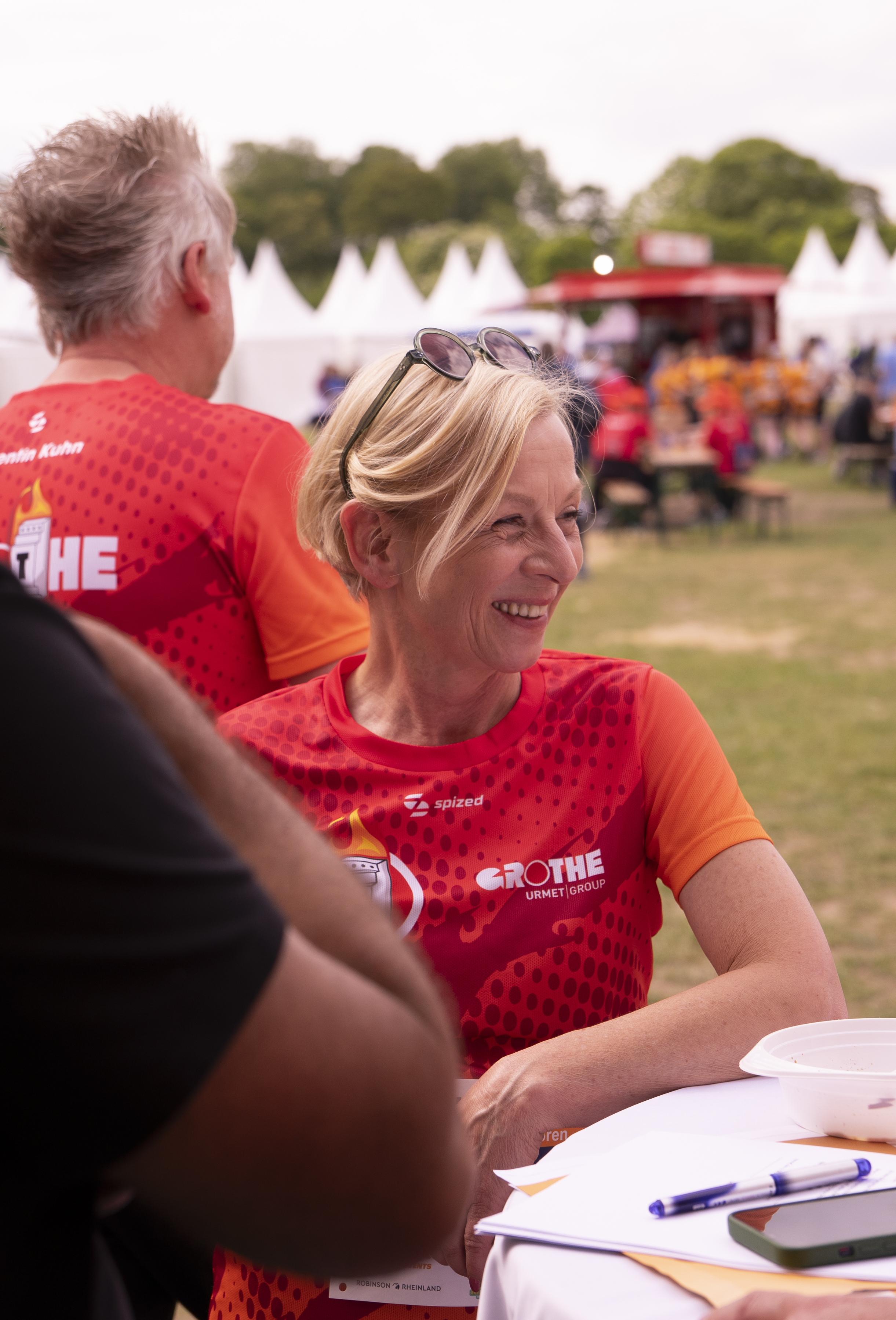 Eine Grothe-Mitarbeiterin im Team-Trikot lehnt sich auf einen Stehtisch und lächelt