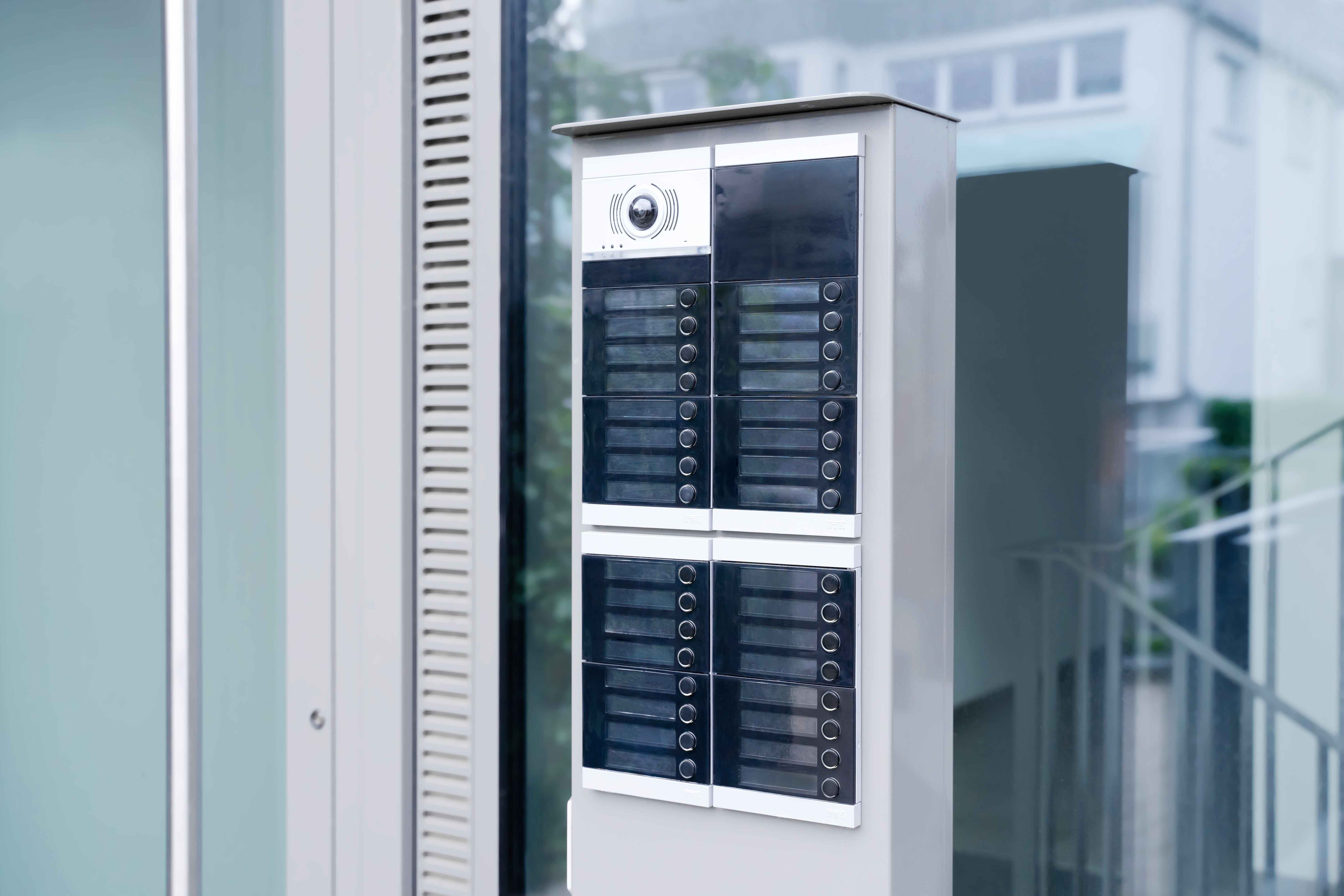 ALPHA-Türstation mit vielen Namensschildern und Klingelknöpfen auf einer Stele vor einem Hauseingang