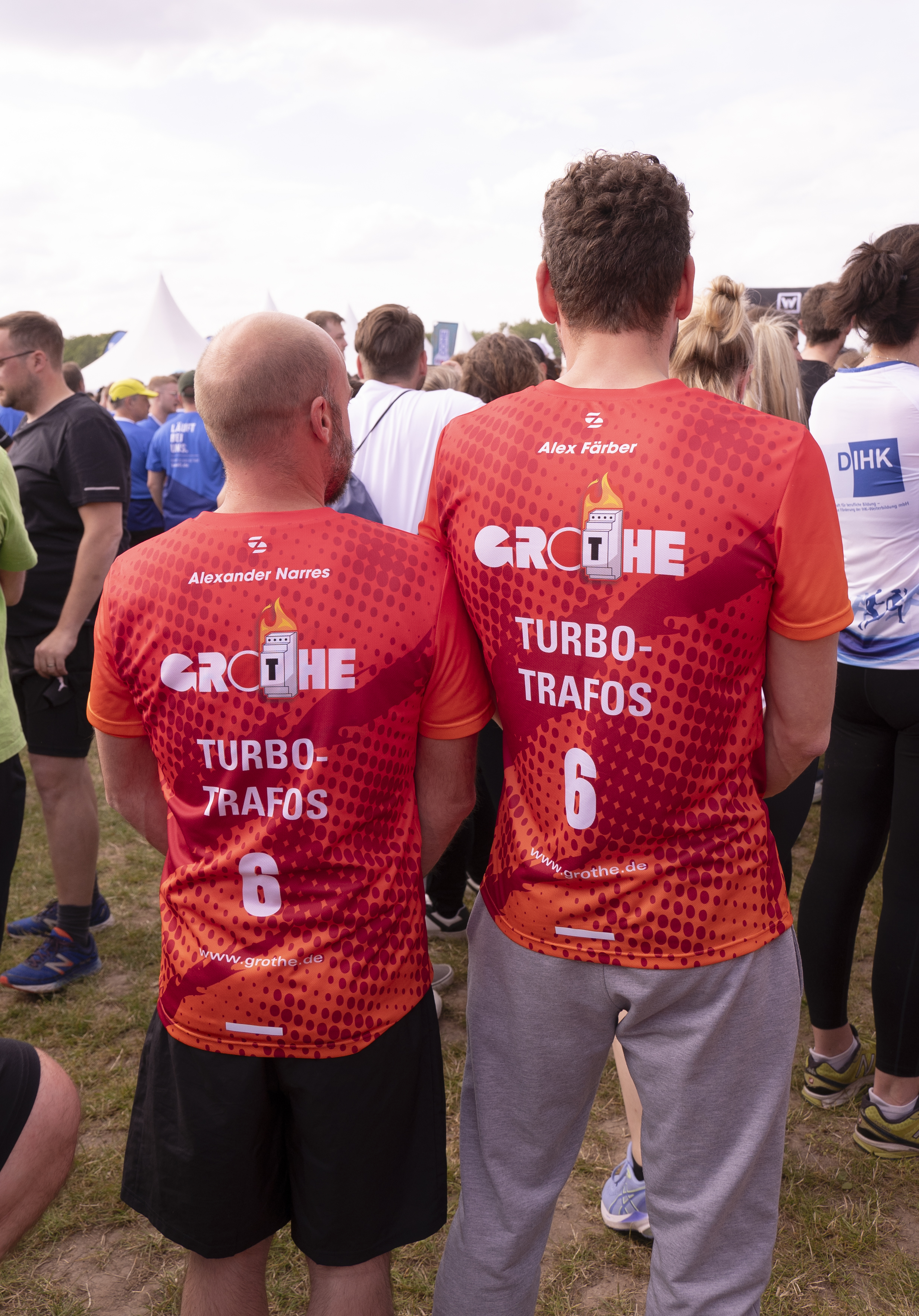 Sicht von hinten: Zwei Grothe-Mitarbeiter in Team-Trikots stehen nebeneinander; auf ihren Rücken ist das Grothe-logo, der Teamname "Turbo-Trafos", Name und eine Rückennummer zu lesen
